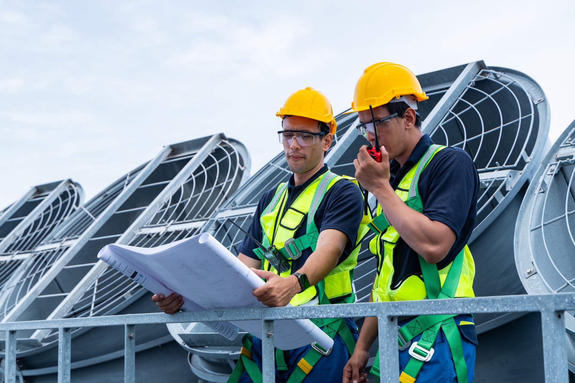 Engineers reviewing HVAC blueprints in an industrial plant room