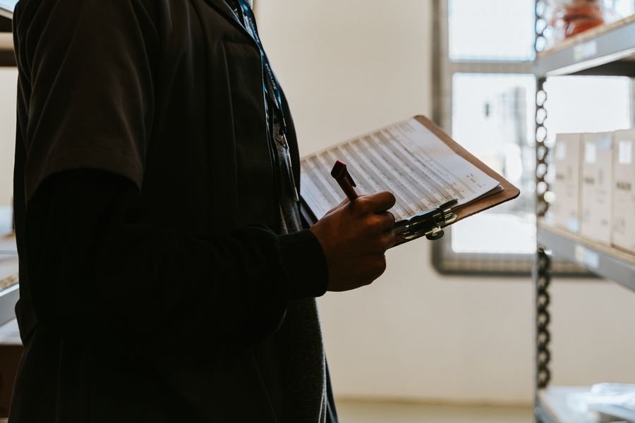 Worker completing checklist with clipboard in warehouse