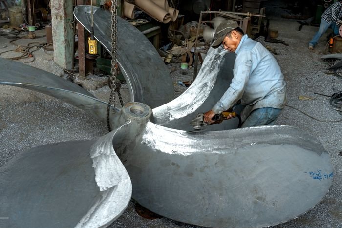 Worker grinding a large industrial fan impeller