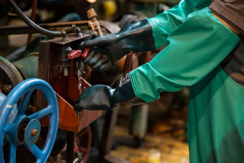 Worker operating industrial valve in gloves