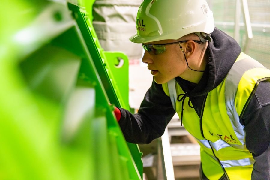 Factory worker in safety helmet inspecting equipment for quality control
