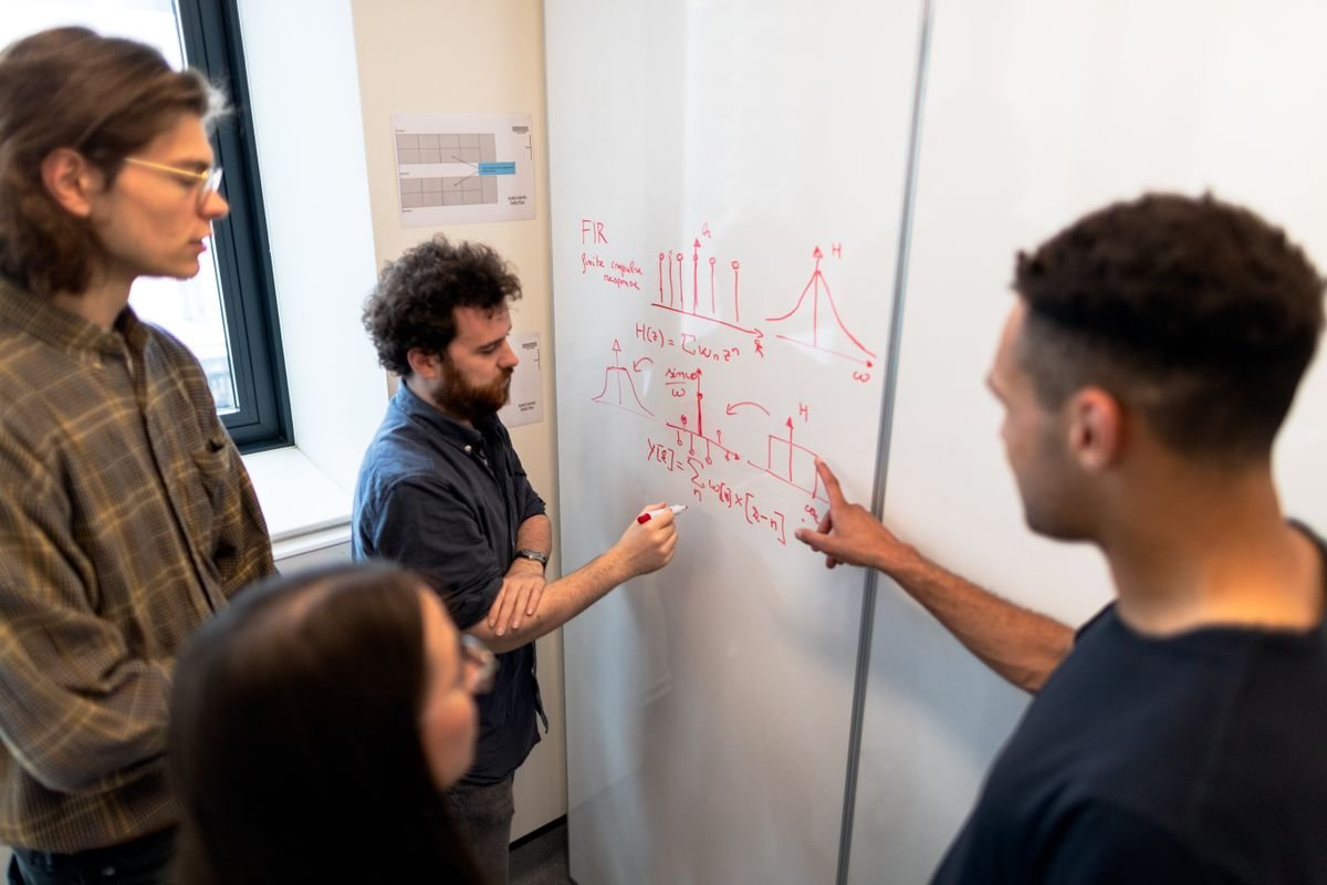 Engineers discussing project data on a whiteboard